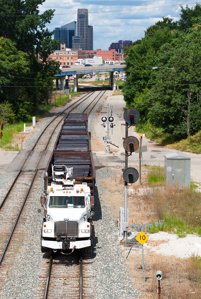 Following an eastbound stone train, this MOW force with ties loaded in the gons are heading out to the Lake Odessa area to unload.  Grand Rapids skyline in the background with a searchlight signal that should be taken down soon.  08/10/13
