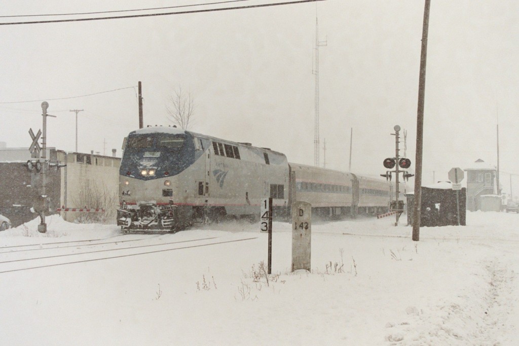 Amtrak P42DC #34
A heavy snowfall greets eastbound Wolverine train #350 as it passes through Kalamazoo, with Genesis #34 in the lead.  In the background,m barely visible is BO Tower.  This train is normally four cars with a locomotive on each end, but this day, for some reason, it did not have a rear engine, and the train was later turned at Detroit, 143 miles ahead. (note the old NYC era cement milepost)  January 2007.
Keywords: Amtrak P42 Genesus 34 350 Wolverine 143 milepost NYC BO Tower interlock junction Kalamazoo