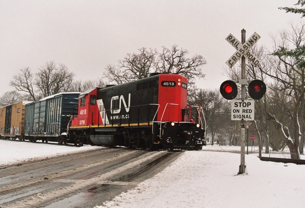 CN GP9R #4618
CN painted GP9R #4618 leads local job CN921, the Kalamazoo Switch Run, past the old crossbucks at the Division St. crossing in Kalamazoo, on the NS Upjohn Industrial.  They had just picked up the Golden West Service boxcar from Arvco Containers, and are moving south to drop off the Railbox boxcar at LC Howard.  On the rear is their caboose, GTW Wide Vision #79054.  GP9R #4618 is a recent CN repaint and formerly sported GTW blue and red colors.  A late season snow highlights the scene.  April 11, 2007.
Keywords: CN921 CN 921 Canadian National Grand Trunk GTW GP9R 4618 Kalamazoo crossbuck crossing