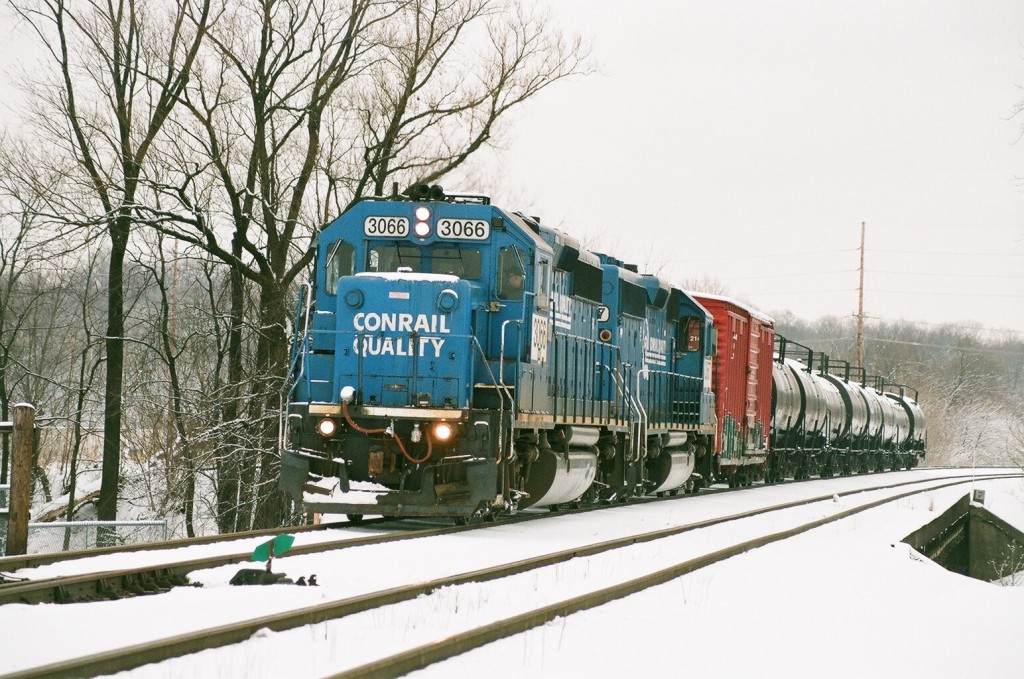 Conrail GP40-2 #3066
Conrail painted GP40-2 leads sequential sister GP40-2 #3067 and a 9 car B-1-G local westbound across the Kalamazoo River Bridge toward BO Tower.  The switch in the foreground is the Harris Crossover.  The tankcars go to Lawton and are the bread and butter of this westward run, while the single 50' boxcar is destined for Niles.  February 5, 2008.
