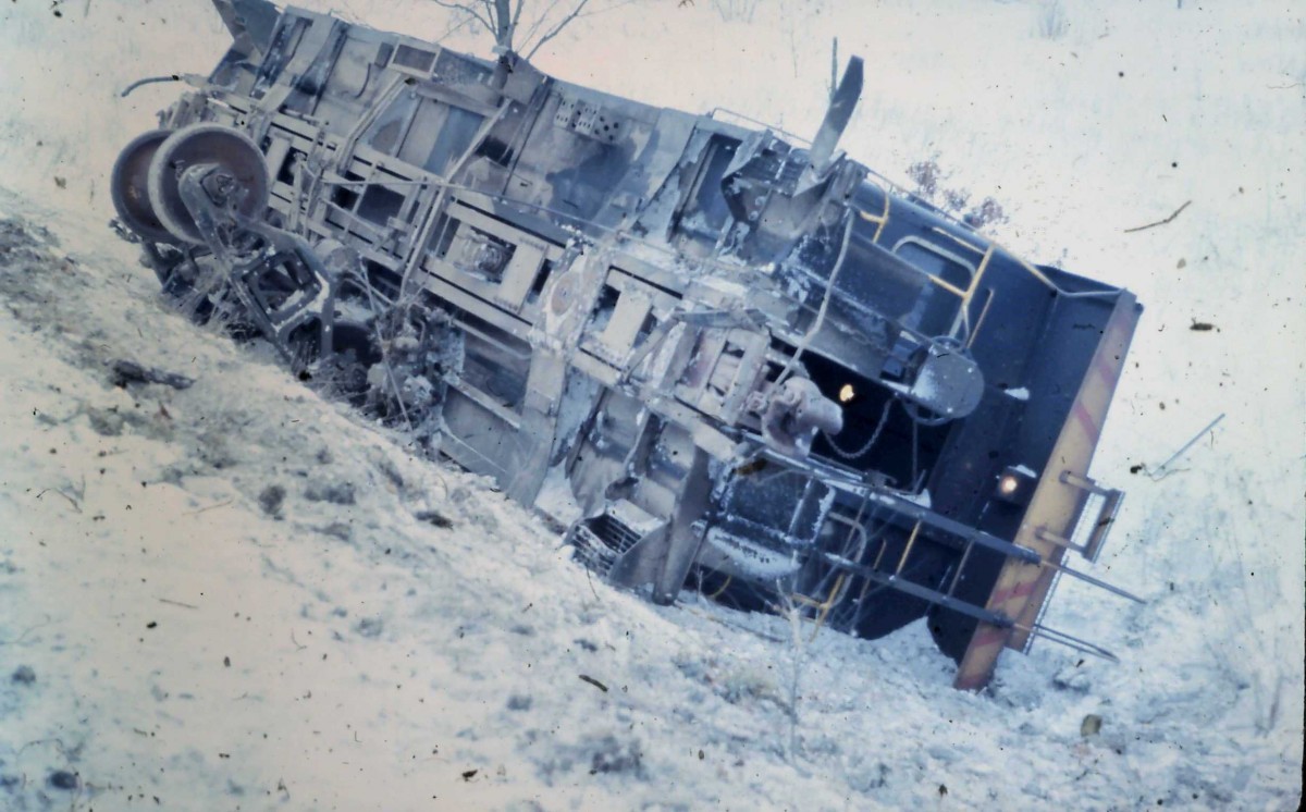 C&O Derailment - Howell, 1976 - Bob M Photo
How did it happen? Here is the entire story, because I was there for it. The date was January 12, 1976, at 5:30am Train 156 from Grand Rapids to Flint, as it crossed the diamond at Ann Pere encountered a broken rail just east of the diamond. The last five cars in the train and the caboose derailed, but all but the caboose, which when down into the ravine, remained upright. 

What was ironic about this, the conductor, who back in the "old days" had their own assigned caboose, that he took with him on whatever job he was on, was on his first trip to Flint with his cab 3160, after many years on the Grand Rapids to Toledo runs. 

On the date of the incident, six inches of new snow had fallen, and within 24 hours after, another foot had fallen. Combined with this and other factors, the caboose was not re-railed and brought up from the ravine until March 17, 1976 after laying there for two months and five days. 
