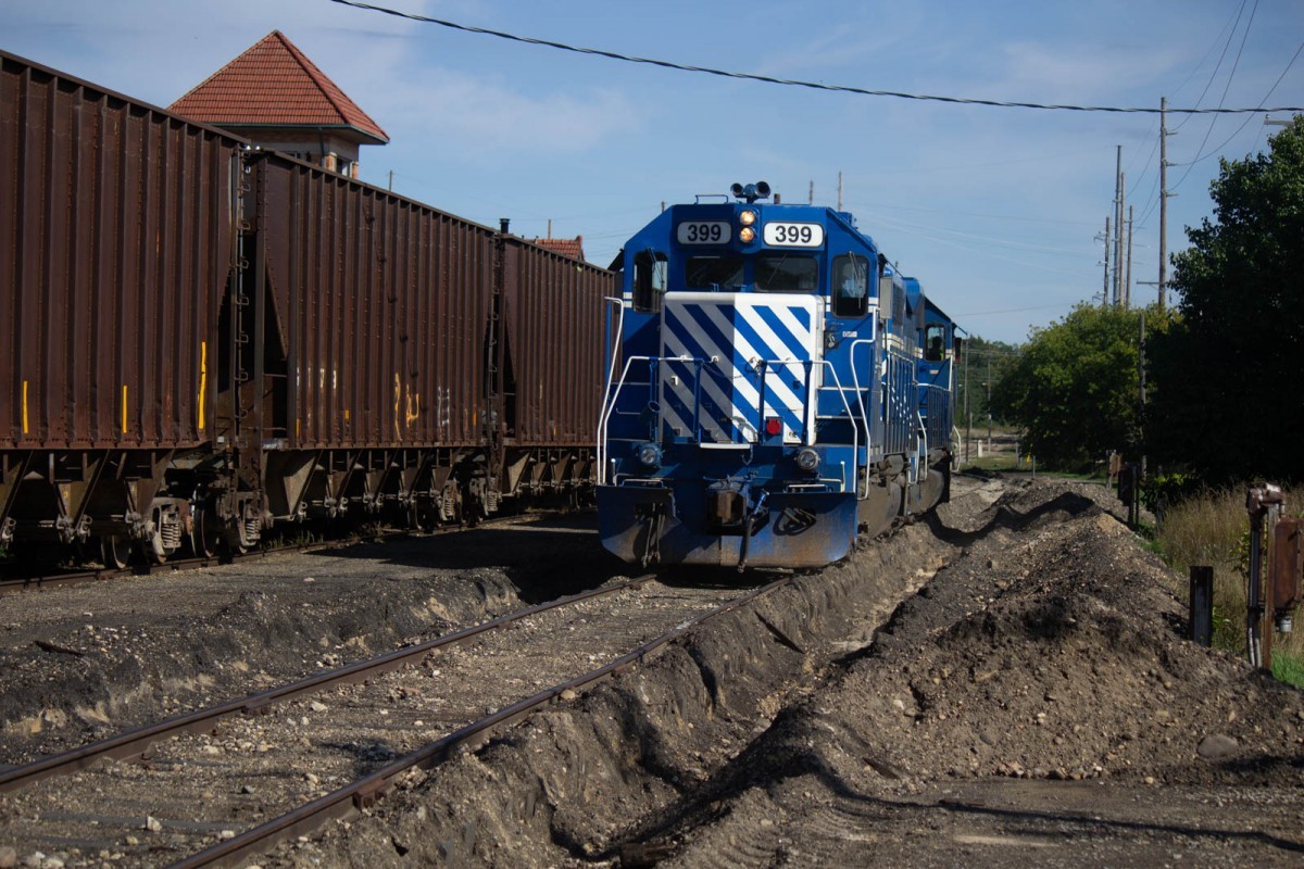 Ballast Train 24 Sept 2019
Dropping the ballast cars along with two empty centerbeams left overnight at the depot, 396/399 begin their run to Bates to retrieve the two more empty cars at Amerhart Wholesale Distribution.
Note the earth work being done along tracks to improve drainage.
